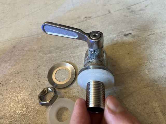 Ein Wasserhahn mit einem Hebel, mehreren Unterlegscheiben und einer Mutter auf einer Arbeitsfläche.