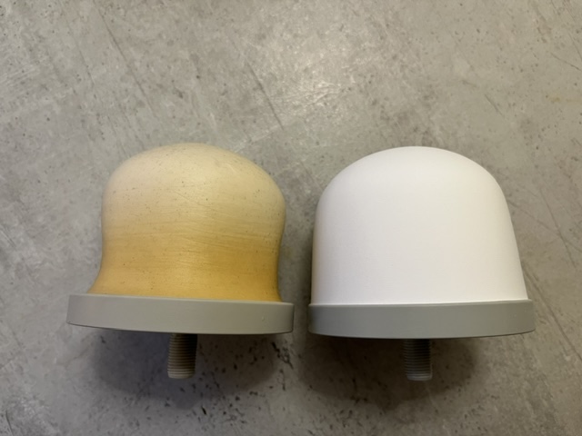 Zwei Kappen mit unterschiedlichen Farben, eine beige und eine weiße, auf einer grauen Unterlage.